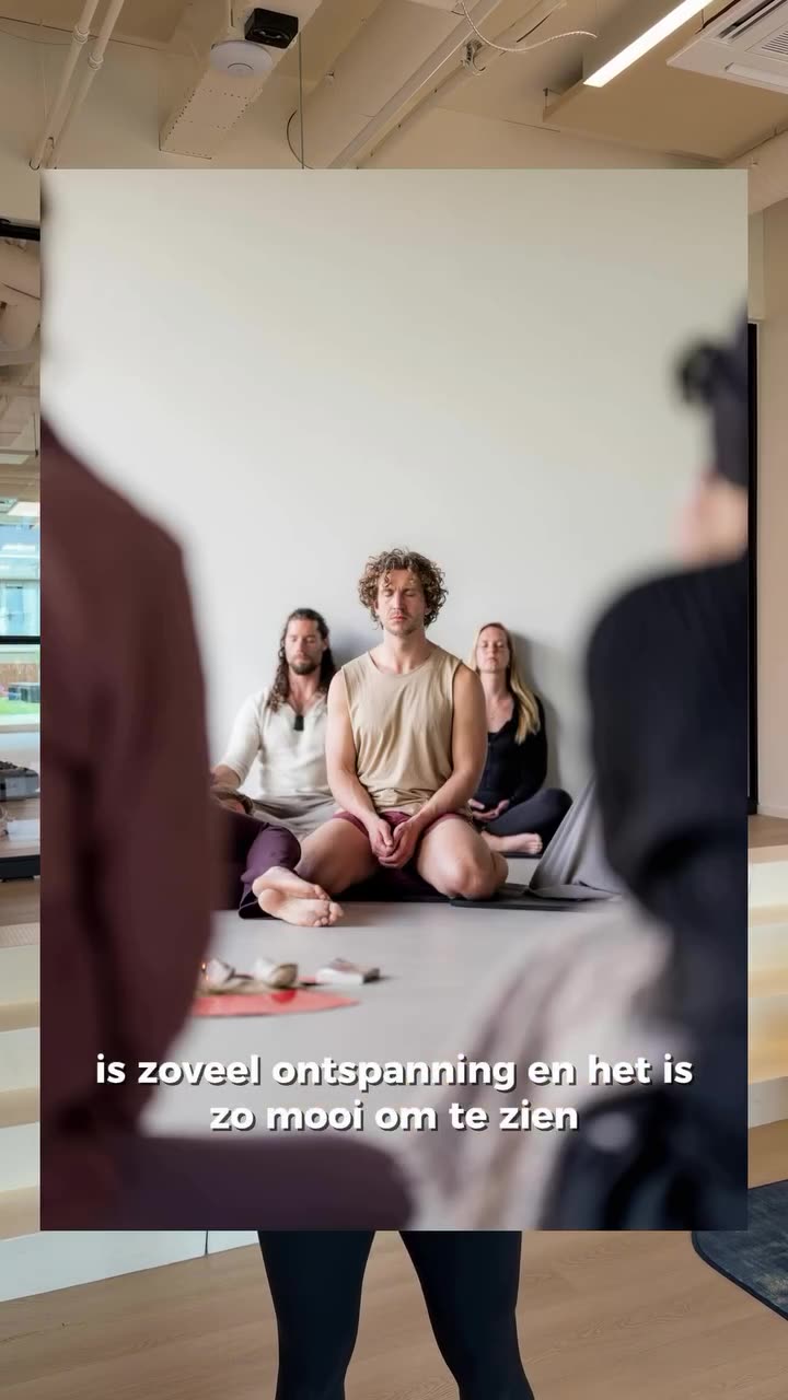 Groep deelnemers zit in een kring op yogamatten en kussens in een lichte studio, met een groen Boeddhabeeldje en een plant op de achtergrond, tijdens een gesprek tijdens de Holistic Movement Experience.